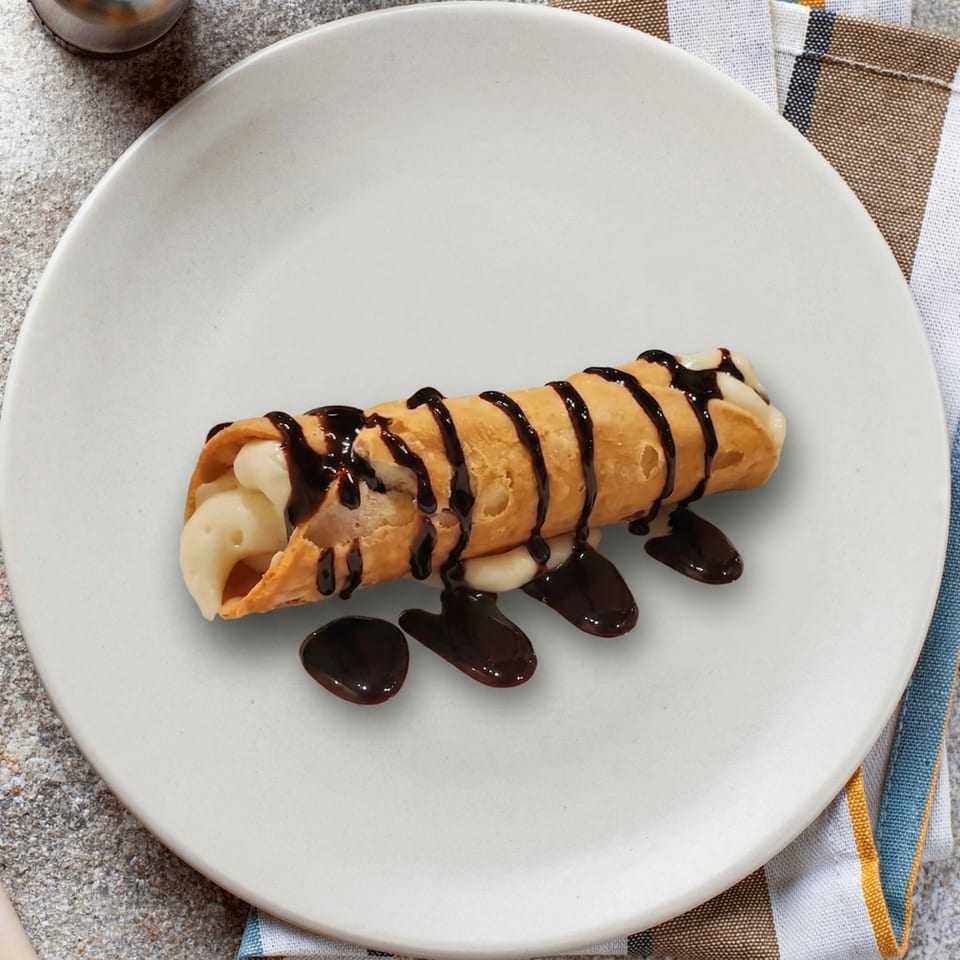 A single cannoli filled with cream and drizzled with chocolate sauce on a white plate.